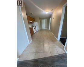 A long hallway with tile flooring and white walls.