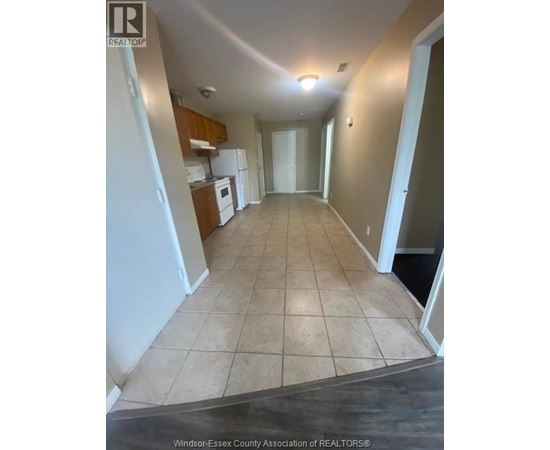 A long hallway with tile flooring and white walls.