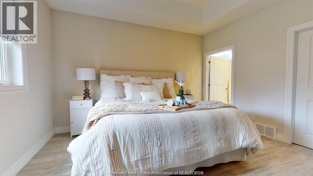 A bedroom with a large bed and a nightstand with a lamp.