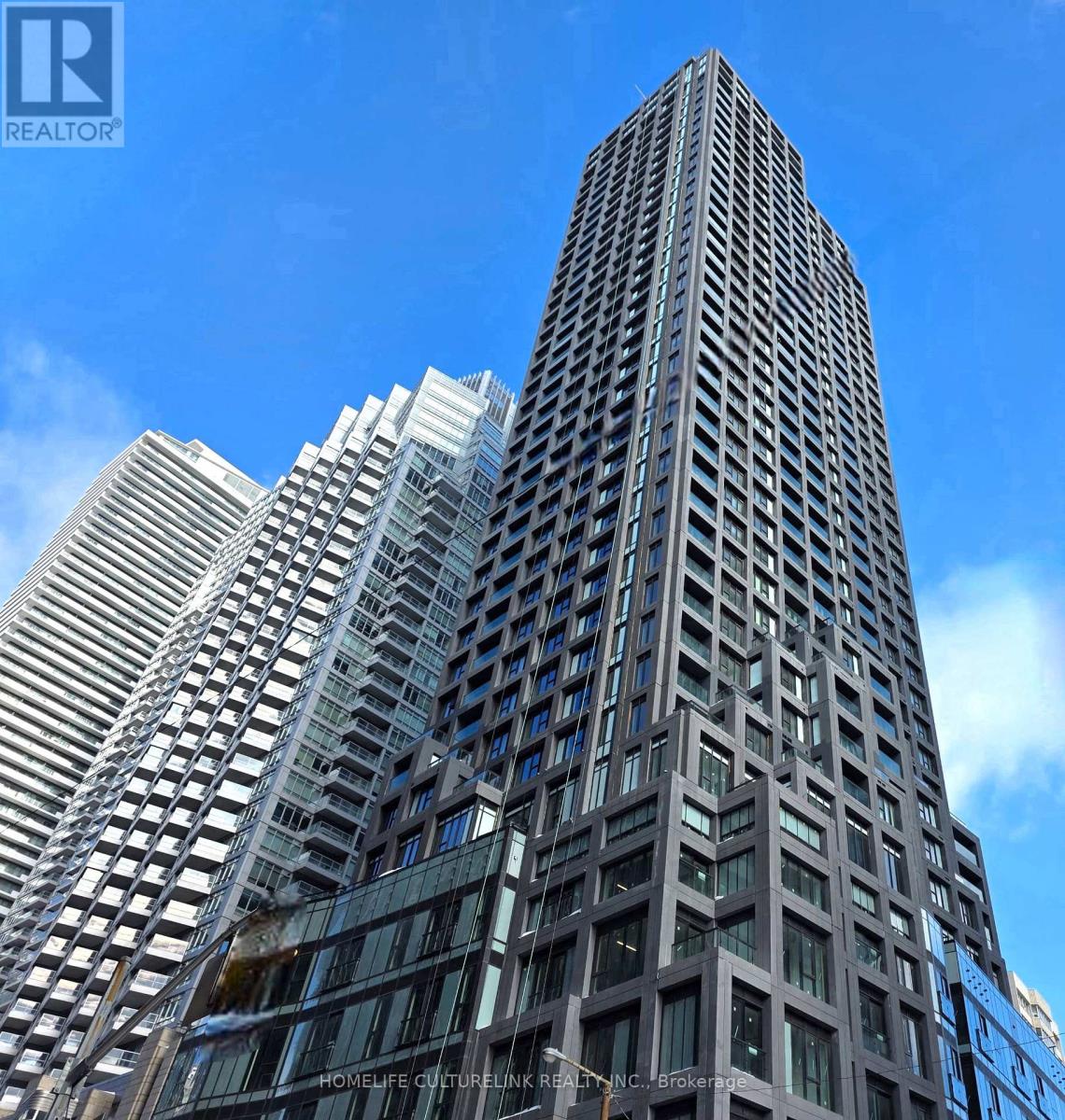 A tall building with many windows is seen against a blue sky.