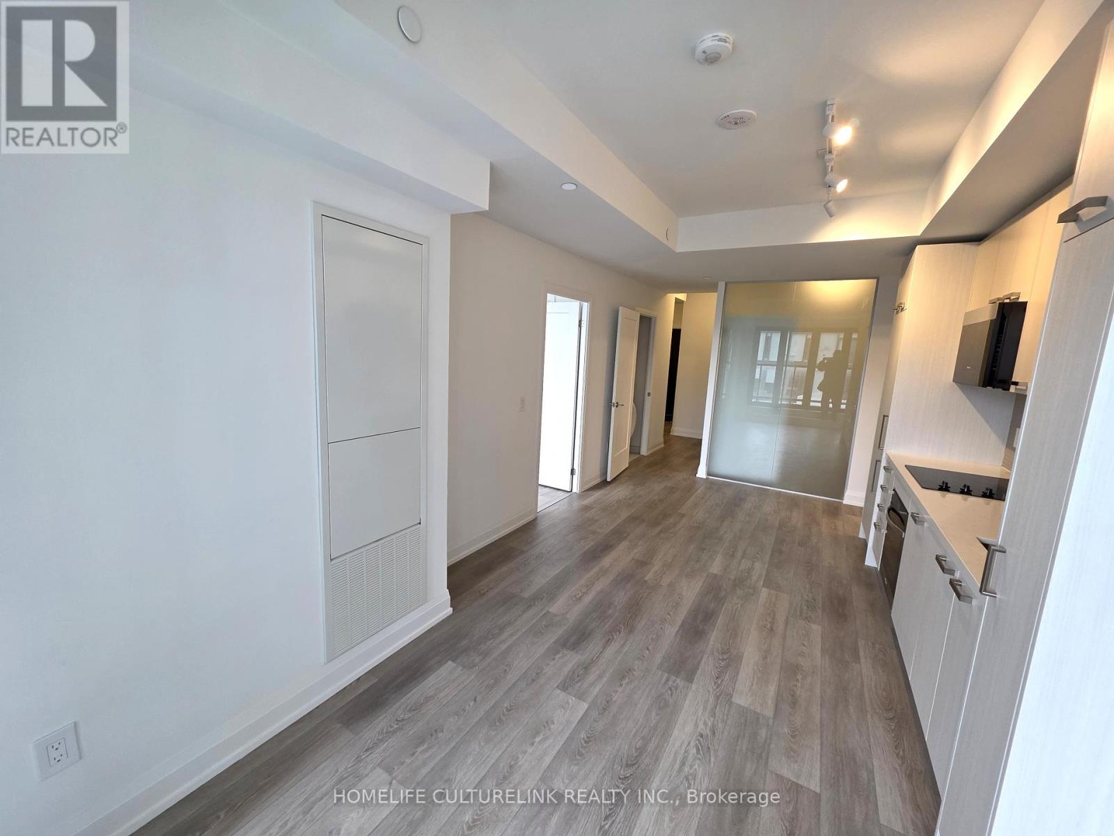 A spacious room with wooden flooring and white walls.
