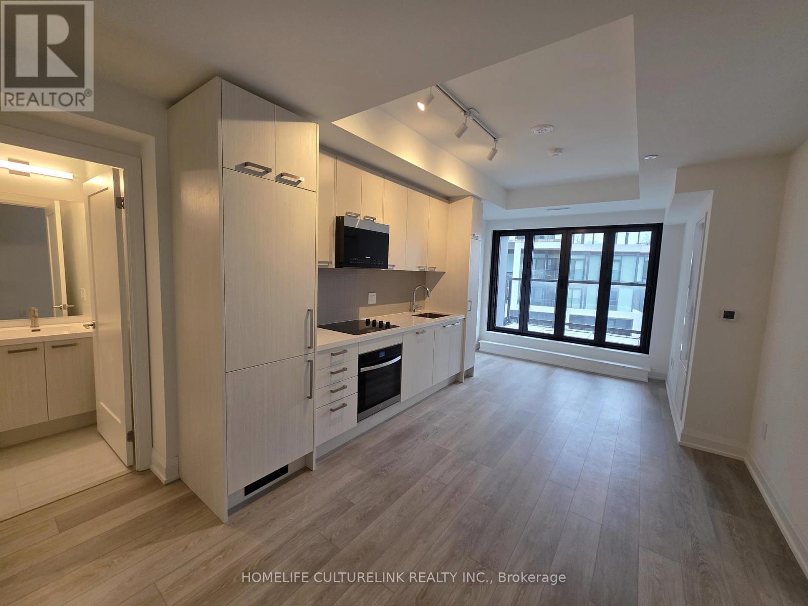 A modern kitchen with white cabinets and a wooden floor.