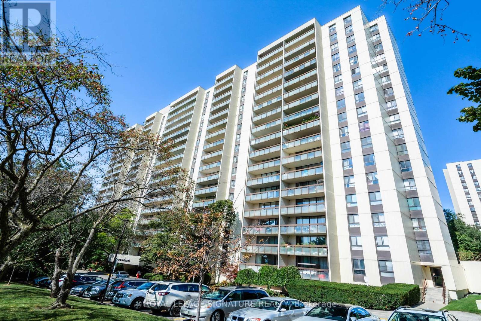 A tall residential building with a parking lot in front.