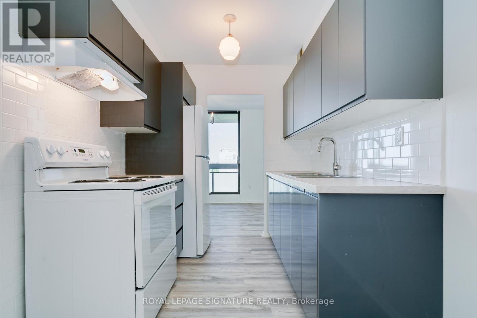 A modern kitchen with white appliances and a wooden floor.