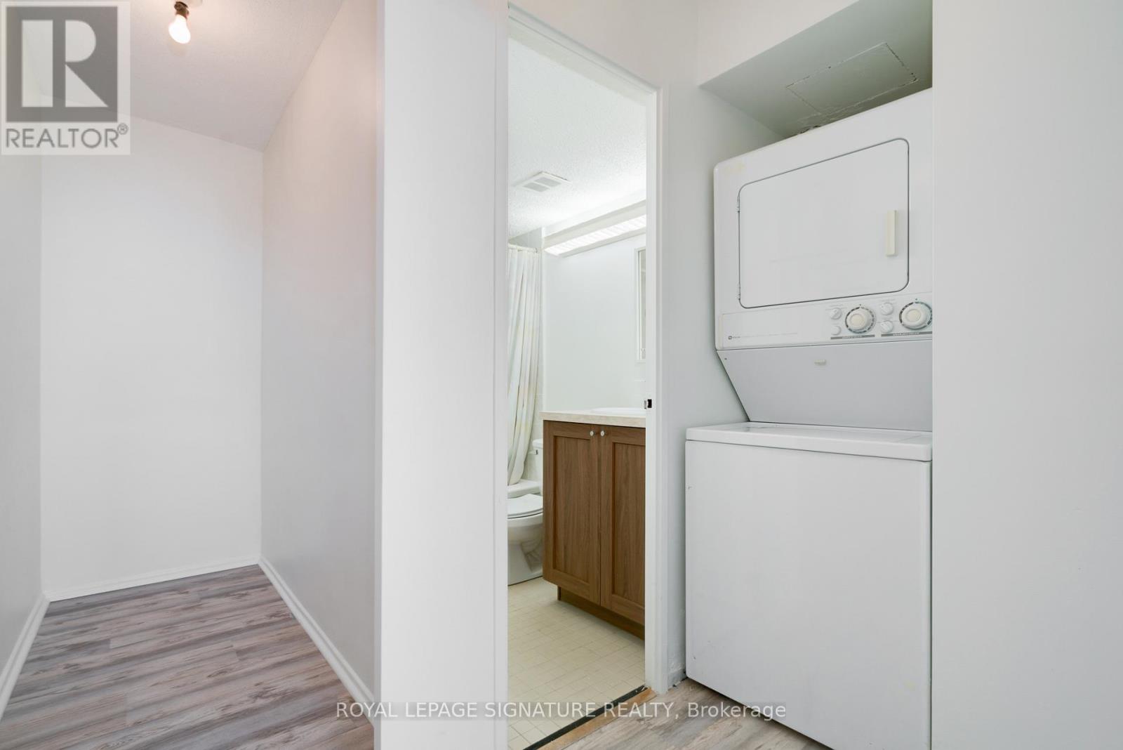 A white refrigerator is in a kitchen with wood flooring.
