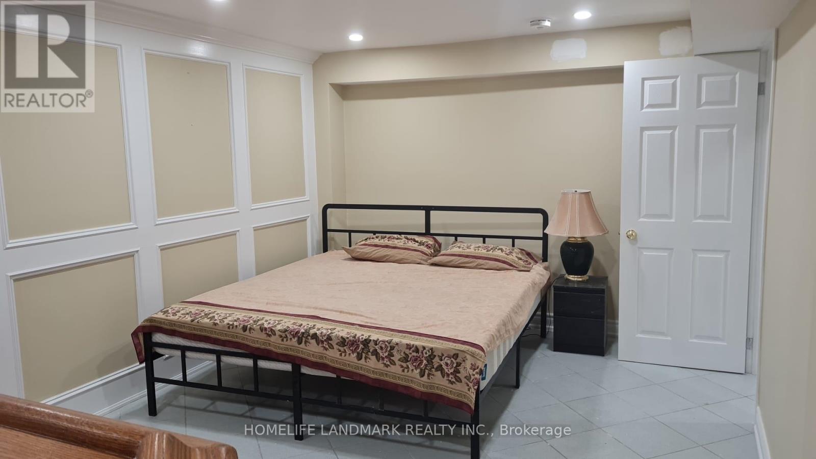 A bedroom with a bed, nightstand, and lamp.