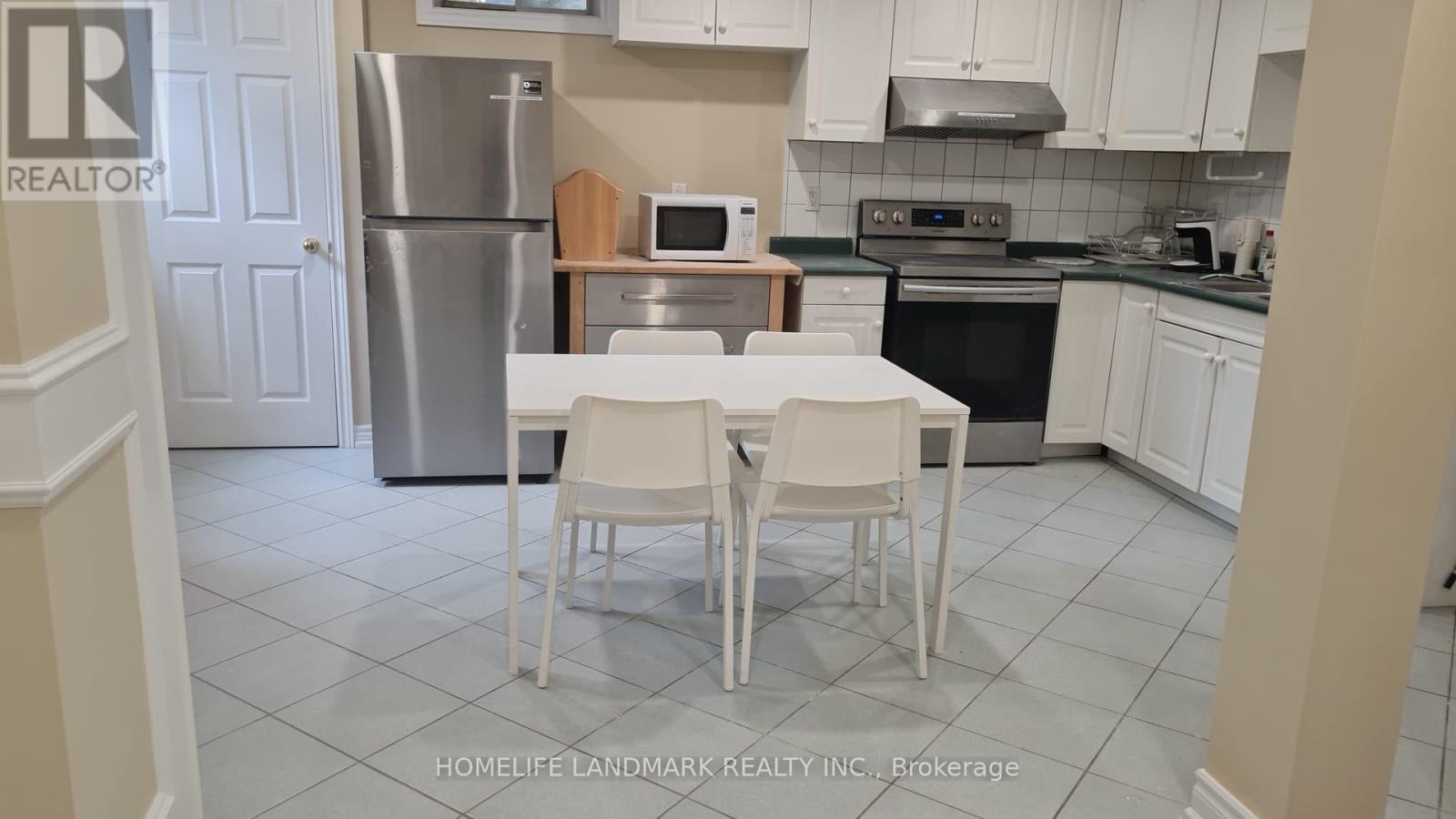 A kitchen with a table and chairs in front of a refrigerator.