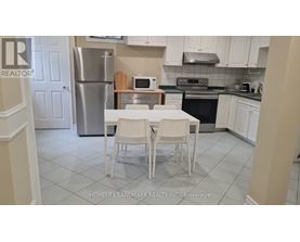 A kitchen with a table and chairs in front of a refrigerator.