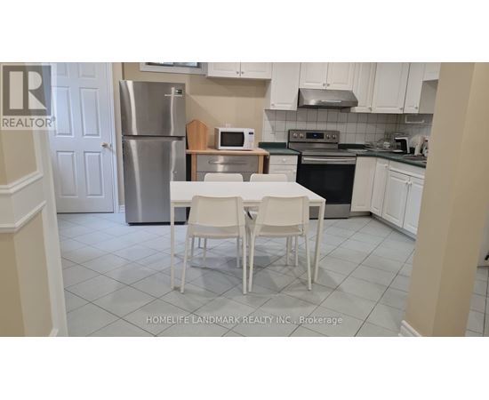 A kitchen with a table and chairs in front of a refrigerator.