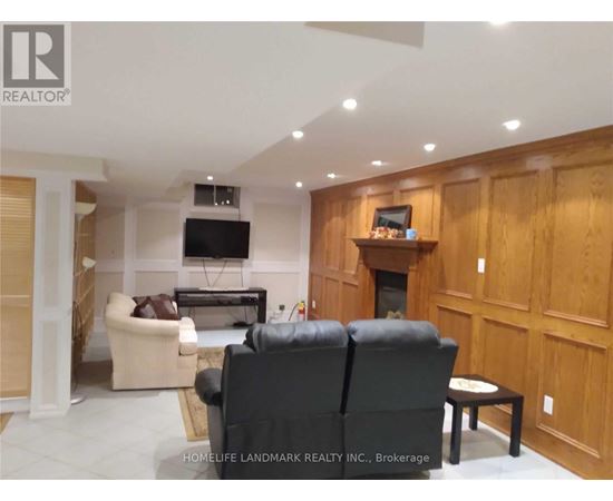 A living room with a black leather couch and a flat screen TV mounted on the wall.