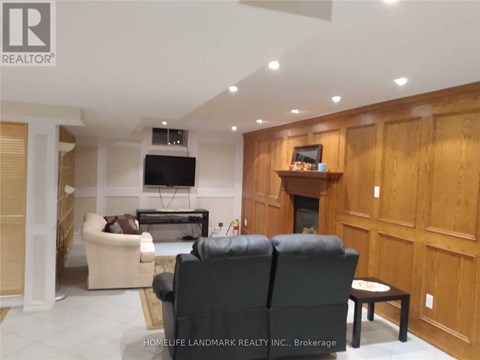 A living room with a black leather couch and a flat screen TV mounted on the wall.