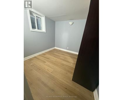 A room with wooden flooring and a window with blinds.