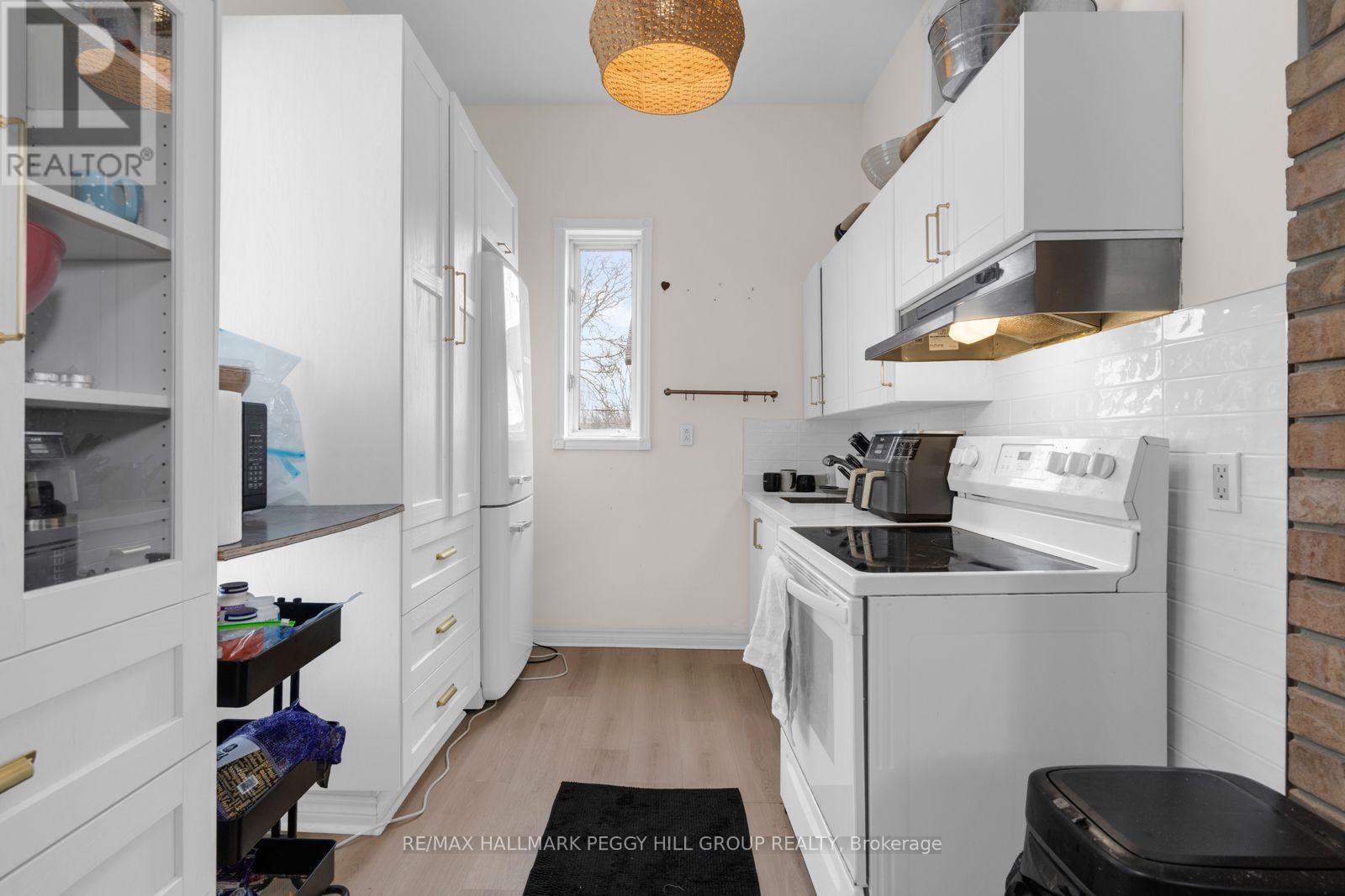 A white kitchen with a black trash bin on the floor.