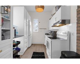 A white kitchen with a black trash bin on the floor.