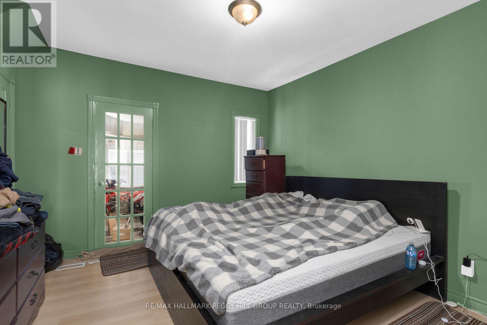 A bedroom with a bed, nightstand, and window.