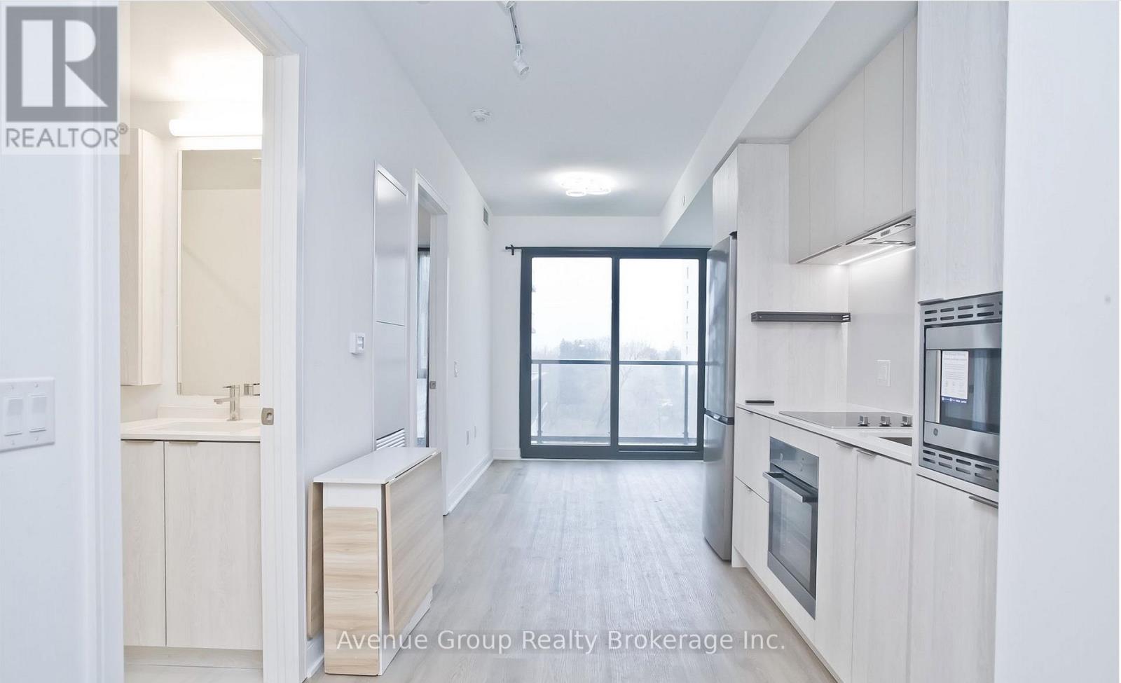 A modern kitchen with white cabinets and a large window.