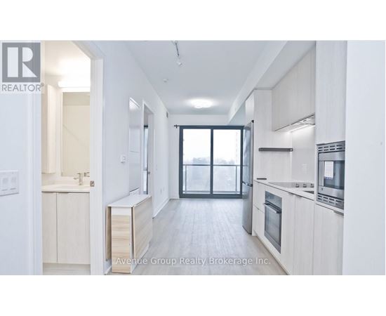 A modern kitchen with white cabinets and a large window.