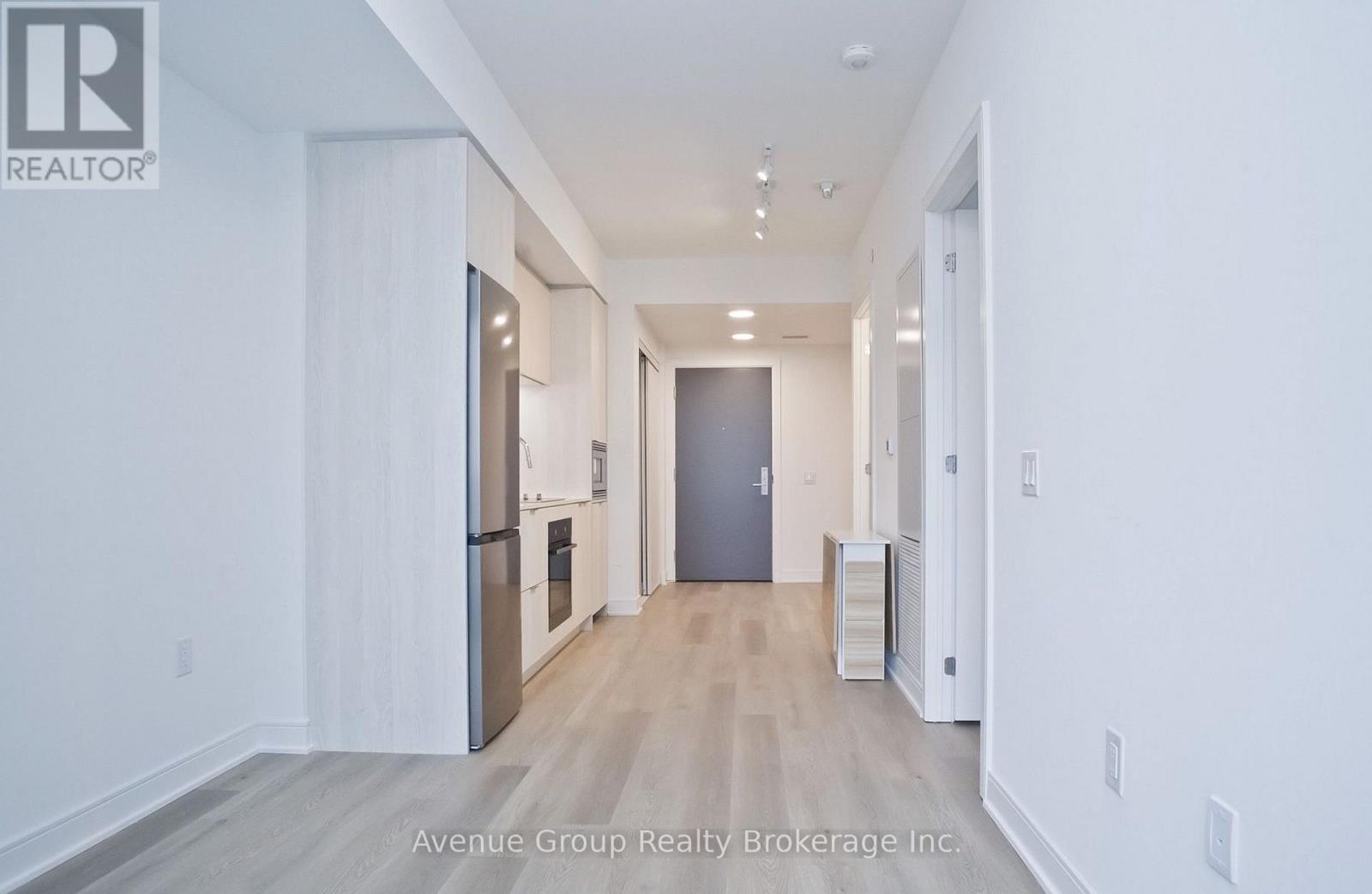 A spacious hallway with a refrigerator and a cabinet on the left side.