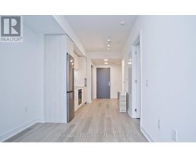 A spacious hallway with a refrigerator and a cabinet on the left side.