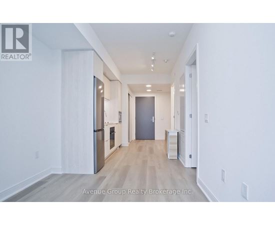 A spacious hallway with a refrigerator and a cabinet on the left side.