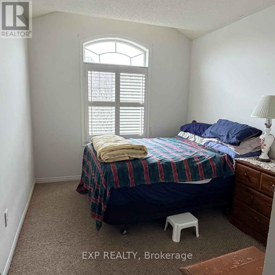 A bedroom with a bed, a window with shutters, and a lamp on a side table.