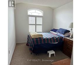 A bedroom with a bed, a window with shutters, and a lamp on a side table.