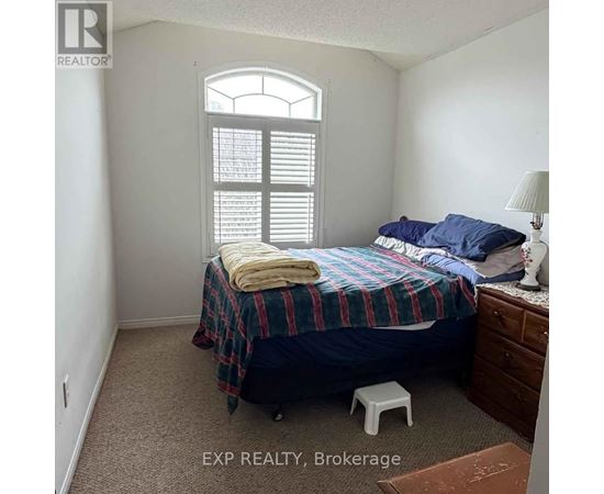 A bedroom with a bed, a window with shutters, and a lamp on a side table.