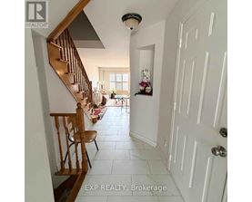 A hallway with a wooden staircase and a white door.