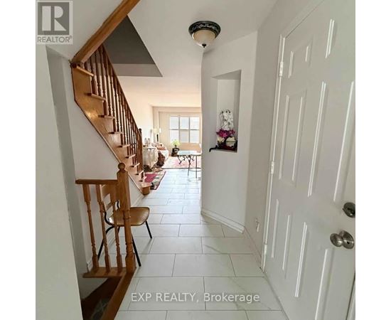 A hallway with a wooden staircase and a white door.