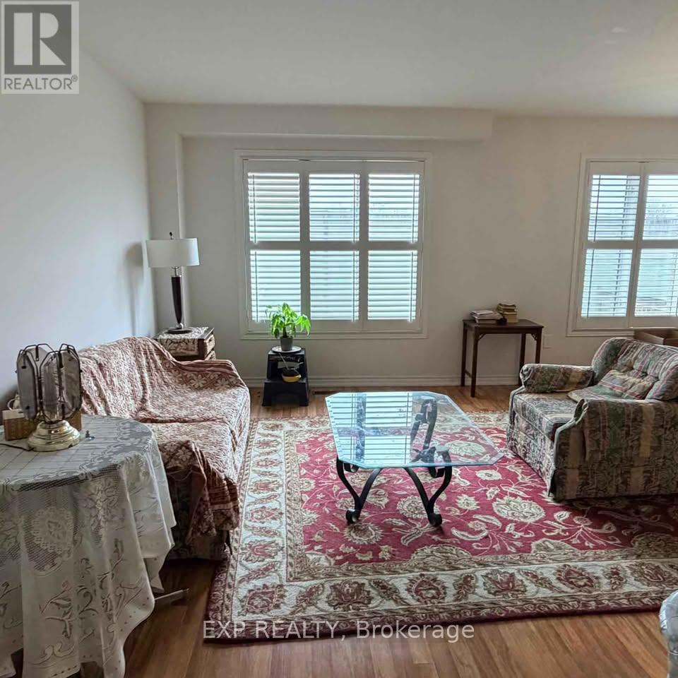 A living room with a glass table and a rug in the middle.