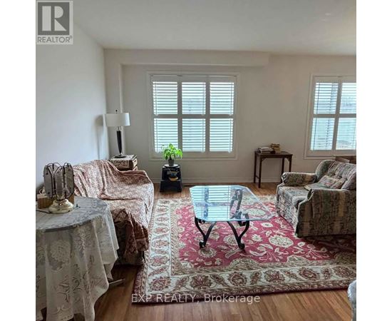 A living room with a glass table and a rug in the middle.