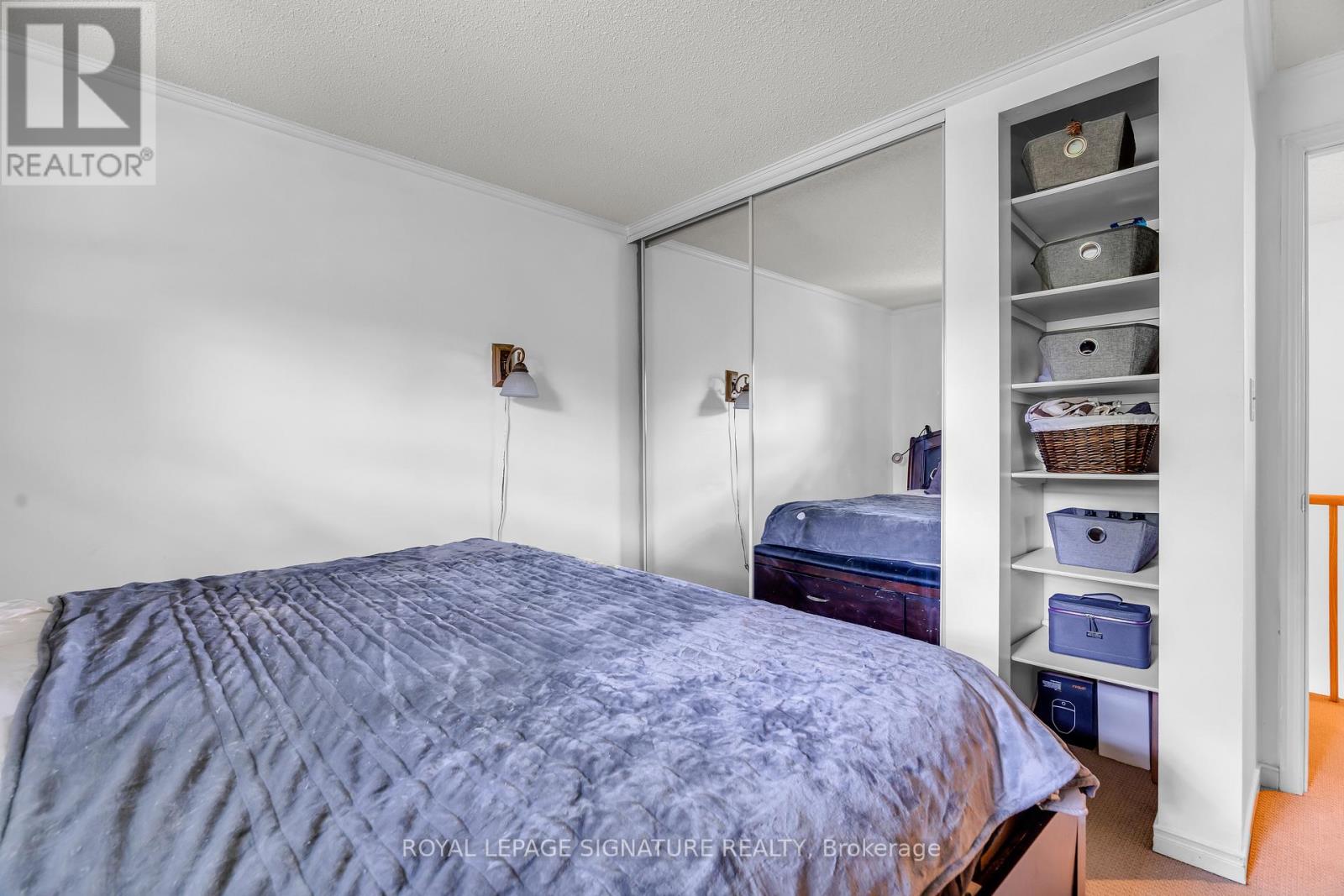 A bedroom with a bed and a closet with shelves.
