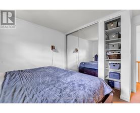 A bedroom with a bed and a closet with shelves.