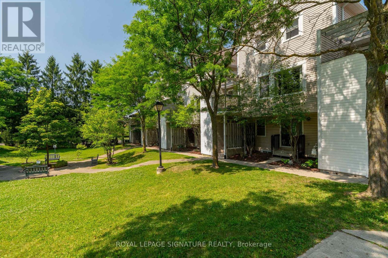 A grassy area in front of a building with a sign that says Royal LePage Signature Realty, Brokerage.