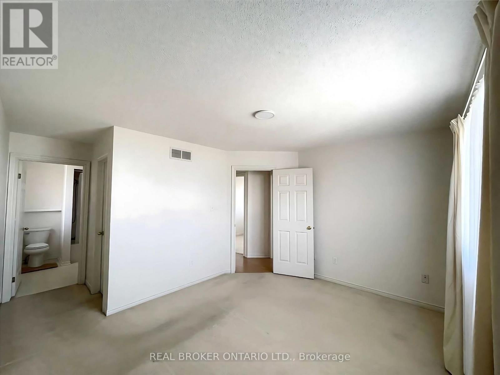 A white bedroom with a door and a window.