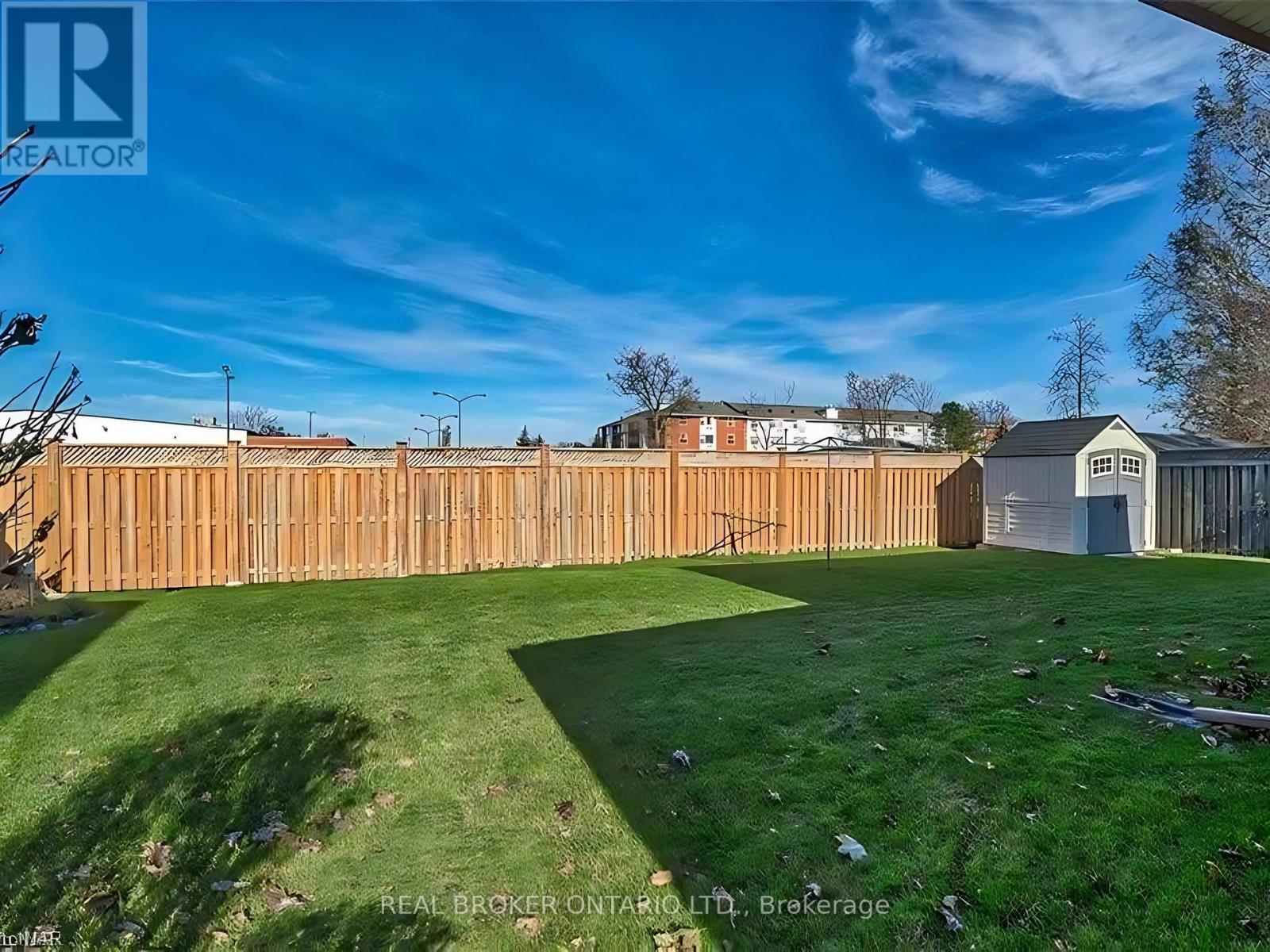 A backyard with a wooden fence and a small building.