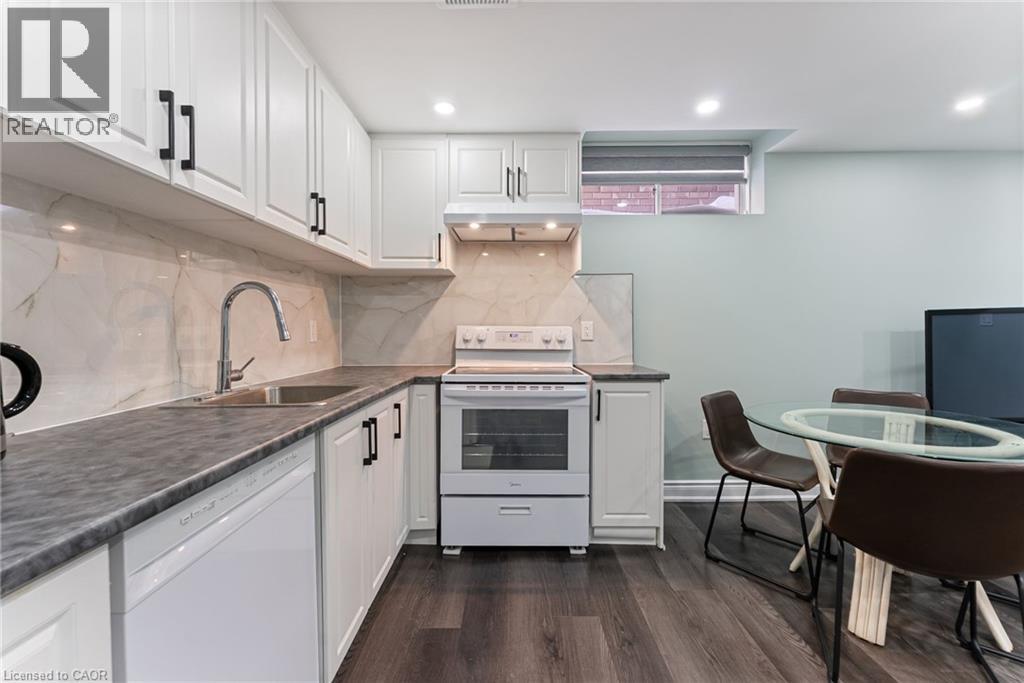 A modern kitchen with white cabinets and a wooden floor.