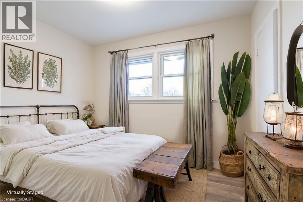 A bedroom with a bed, nightstand, and a plant.