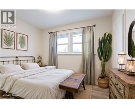A bedroom with a bed, nightstand, and a plant.