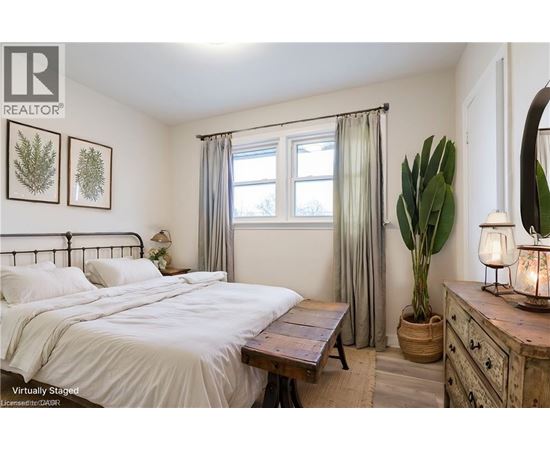 A bedroom with a bed, nightstand, and a plant.