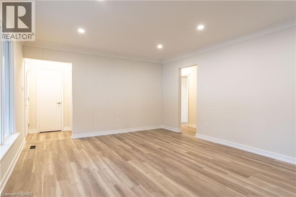 A spacious room with wooden flooring and white walls.