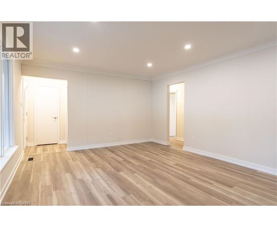 A spacious room with wooden flooring and white walls.