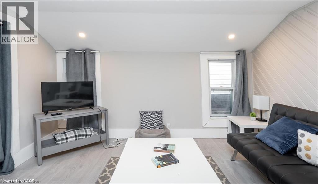 A living room with a black couch, a television, and a window with curtains.