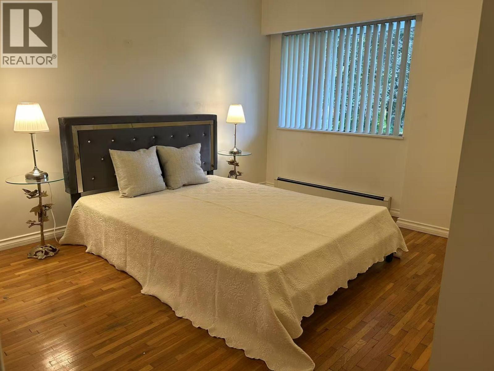 A bedroom with a large bed and two lamps.