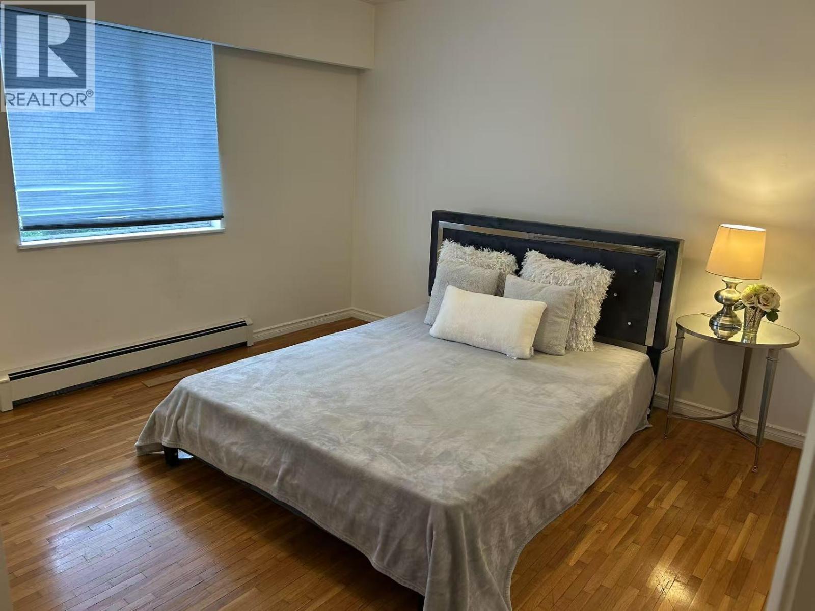 A bedroom with a bed, nightstand, and lamp.