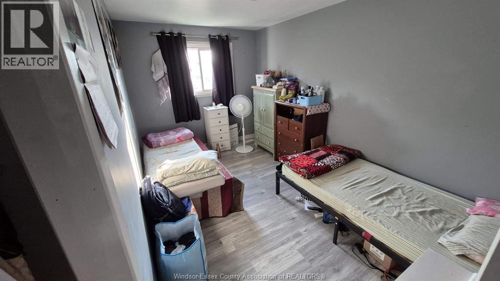 A bedroom with a bed, dresser, and window with curtains.