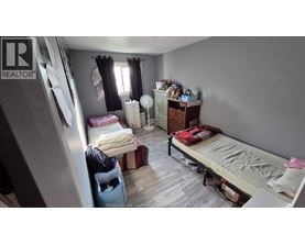 A bedroom with a bed, dresser, and window with curtains.
