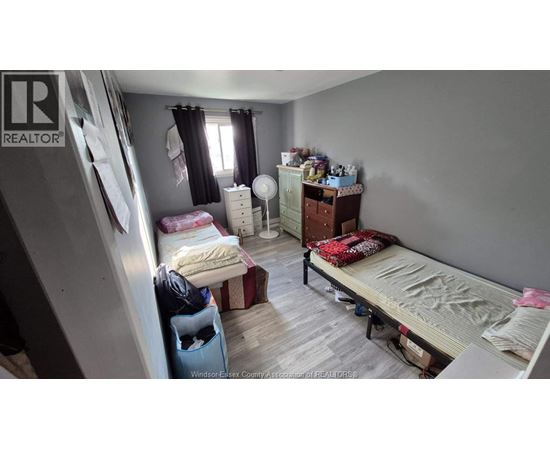 A bedroom with a bed, dresser, and window with curtains.
