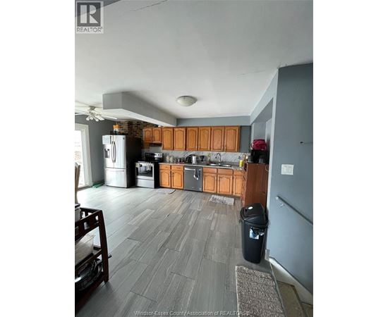 A kitchen with wooden cabinets and a black trash can.