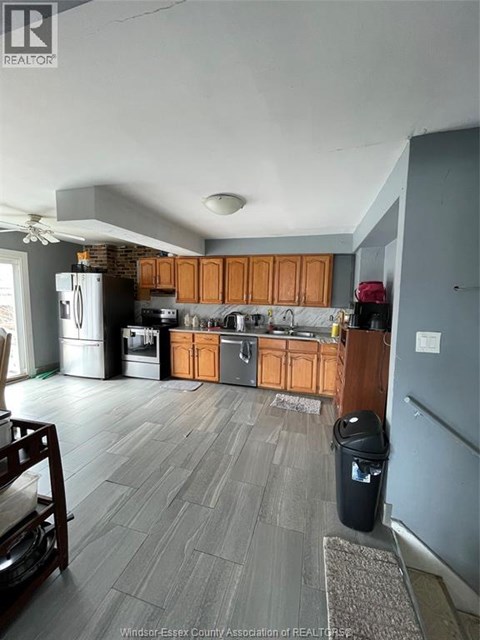 A kitchen with wooden cabinets and a black trash can.